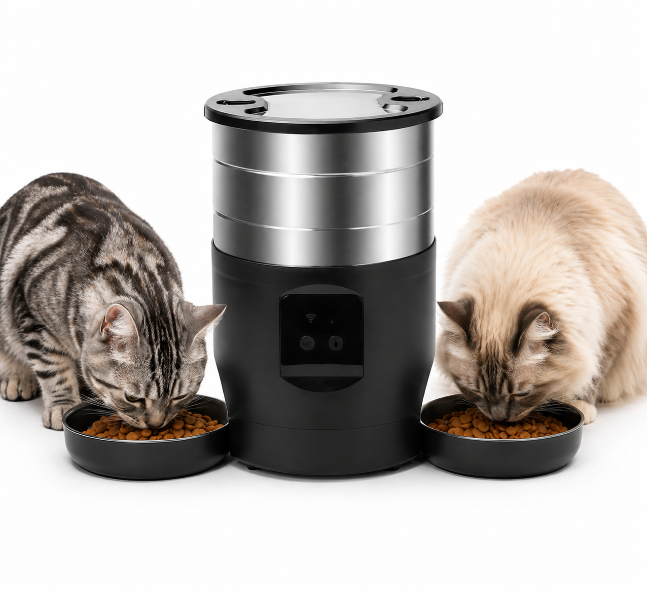 Two cats eating from bowls next to a black and silver pet feeder on a white background